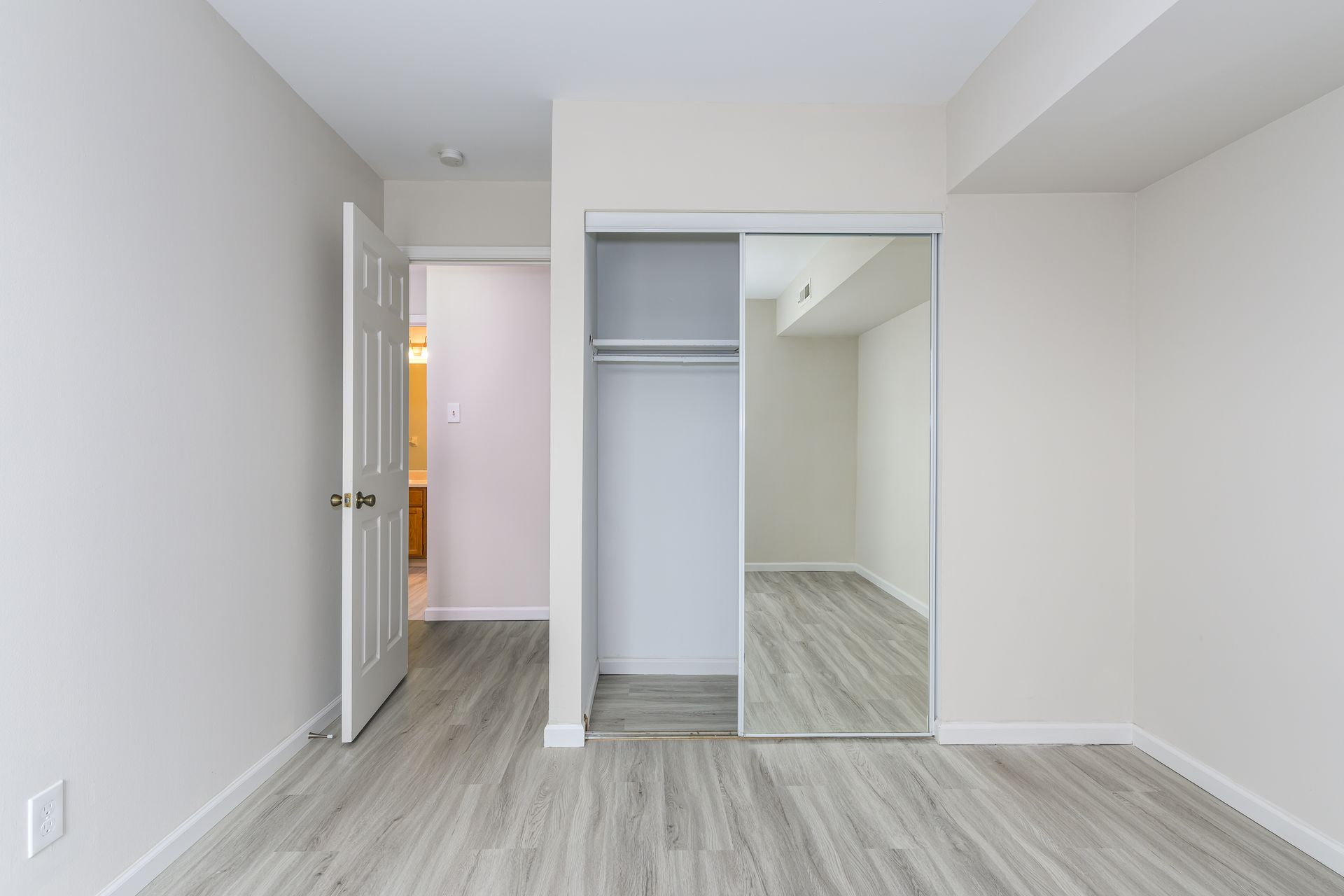 An empty bedroom with a closet and a mirror.