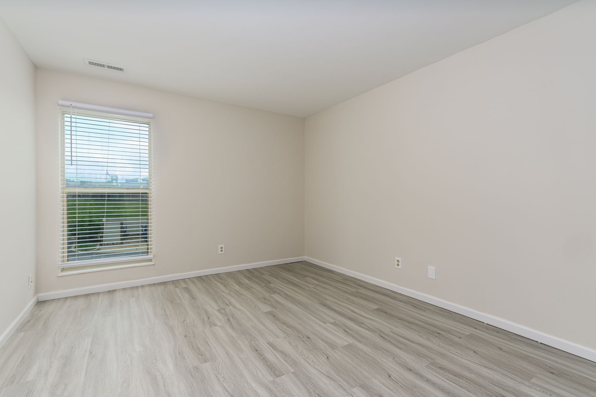 An empty room with hardwood floors and a window.
