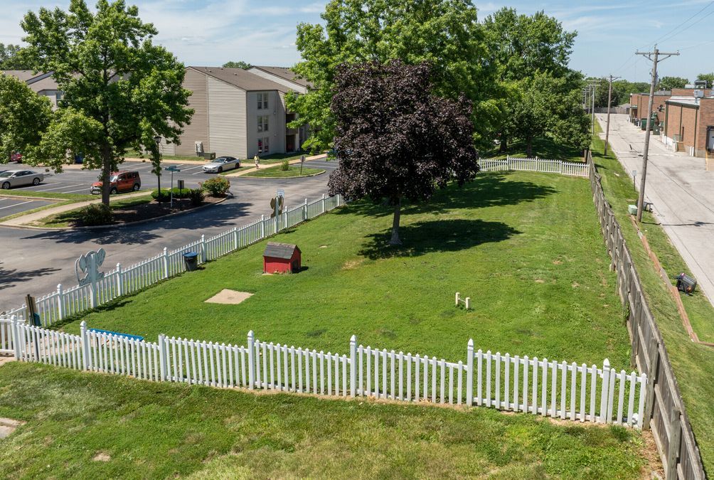 An aerial view of a dog park with a white picket fence surrounding it.