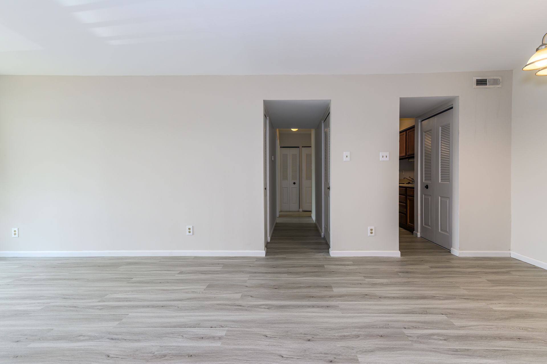 An empty living room with hardwood floors and white walls.