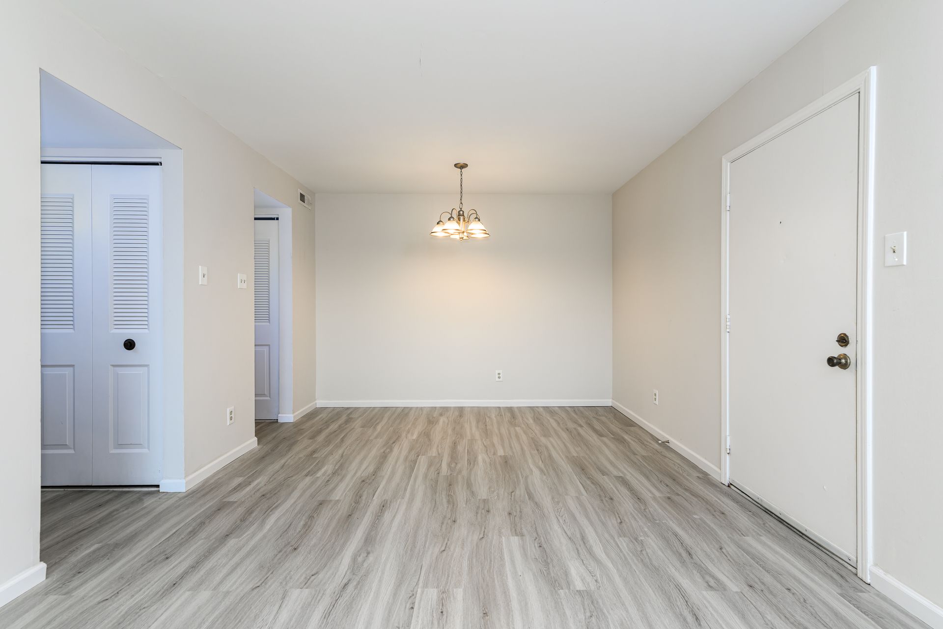 An empty living room with hardwood floors and white walls.