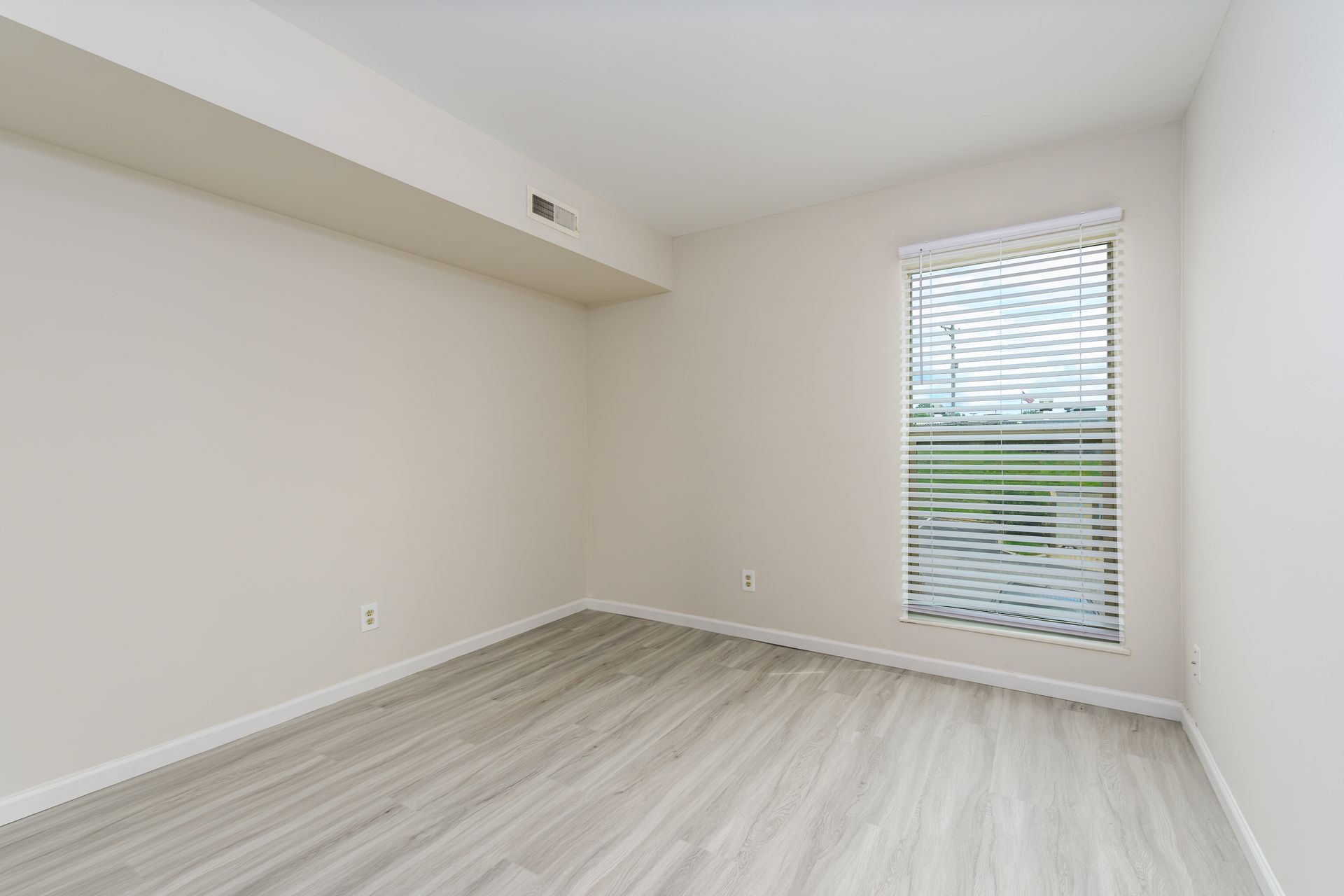 An empty bedroom with a window and blinds.