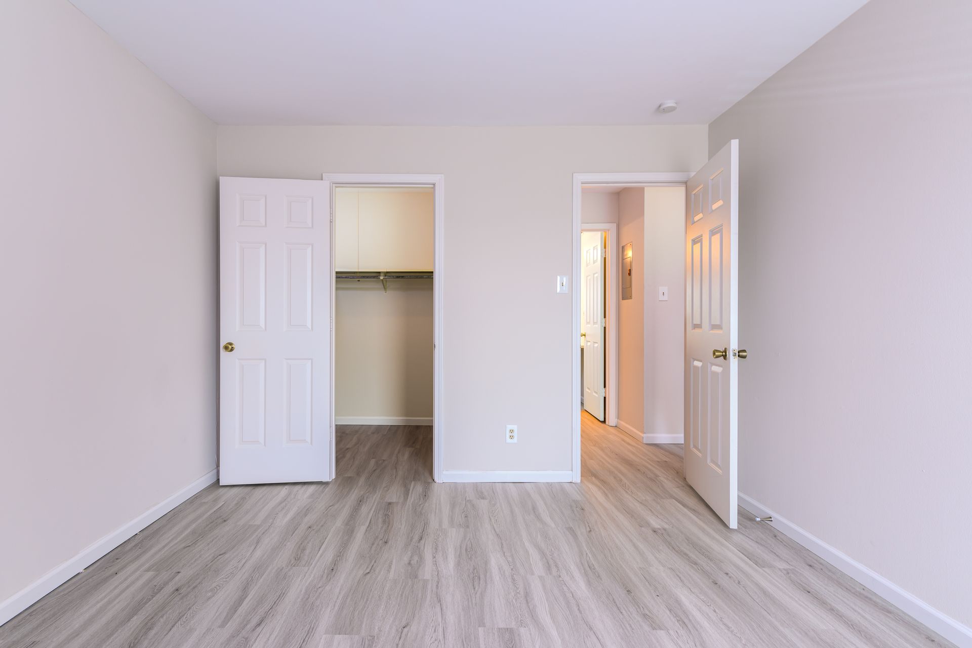 An empty bedroom with hardwood floors and a closet.