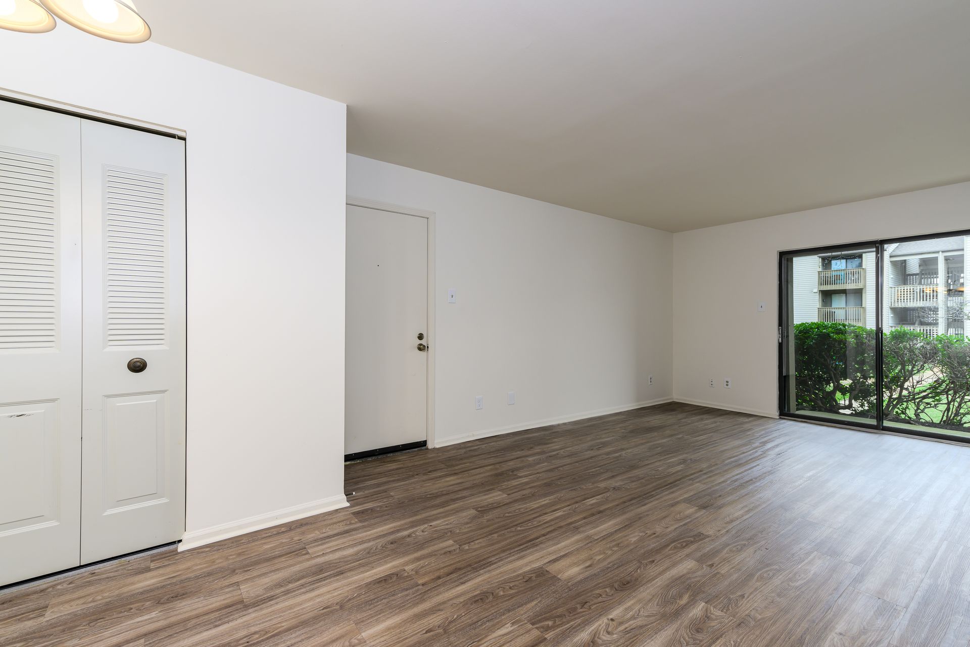 An empty living room with hardwood floors and white walls.