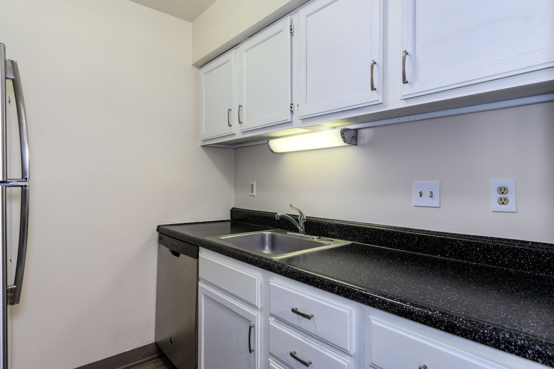 A kitchen with white cabinets and black counter tops