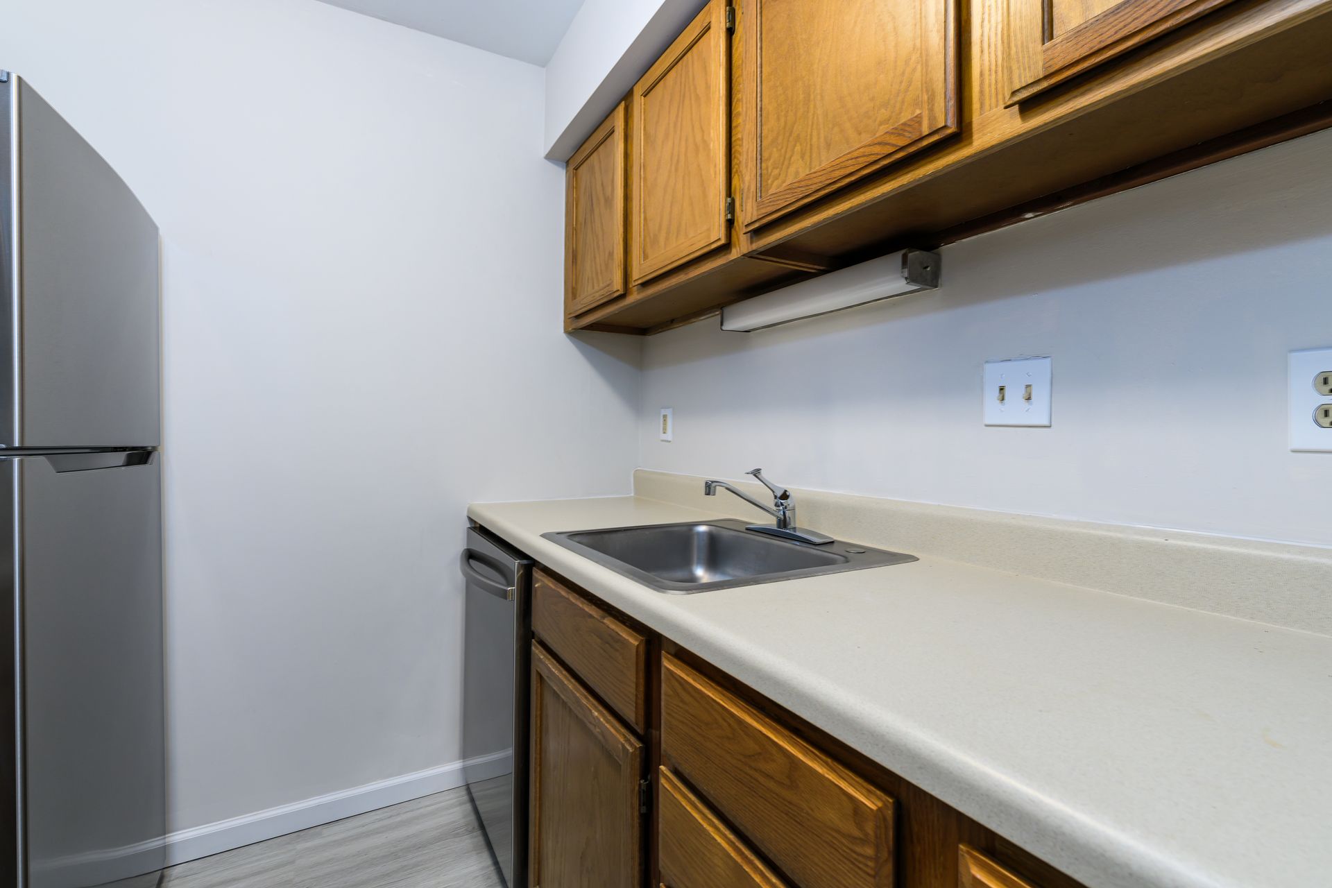 A kitchen with a sink , refrigerator and dishwasher.