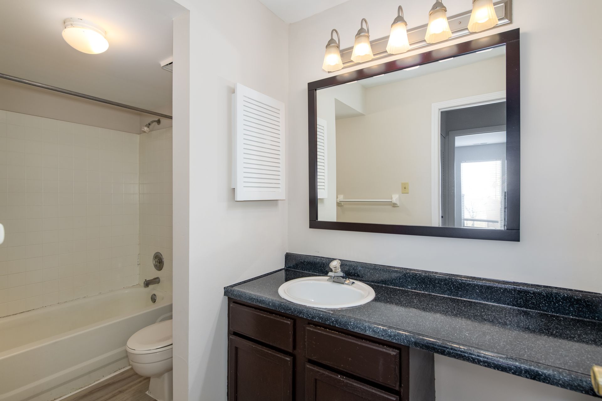 A bathroom with a sink , toilet , bathtub and mirror.