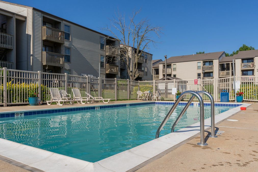 A large swimming pool with stairs leading to it in front of a building.