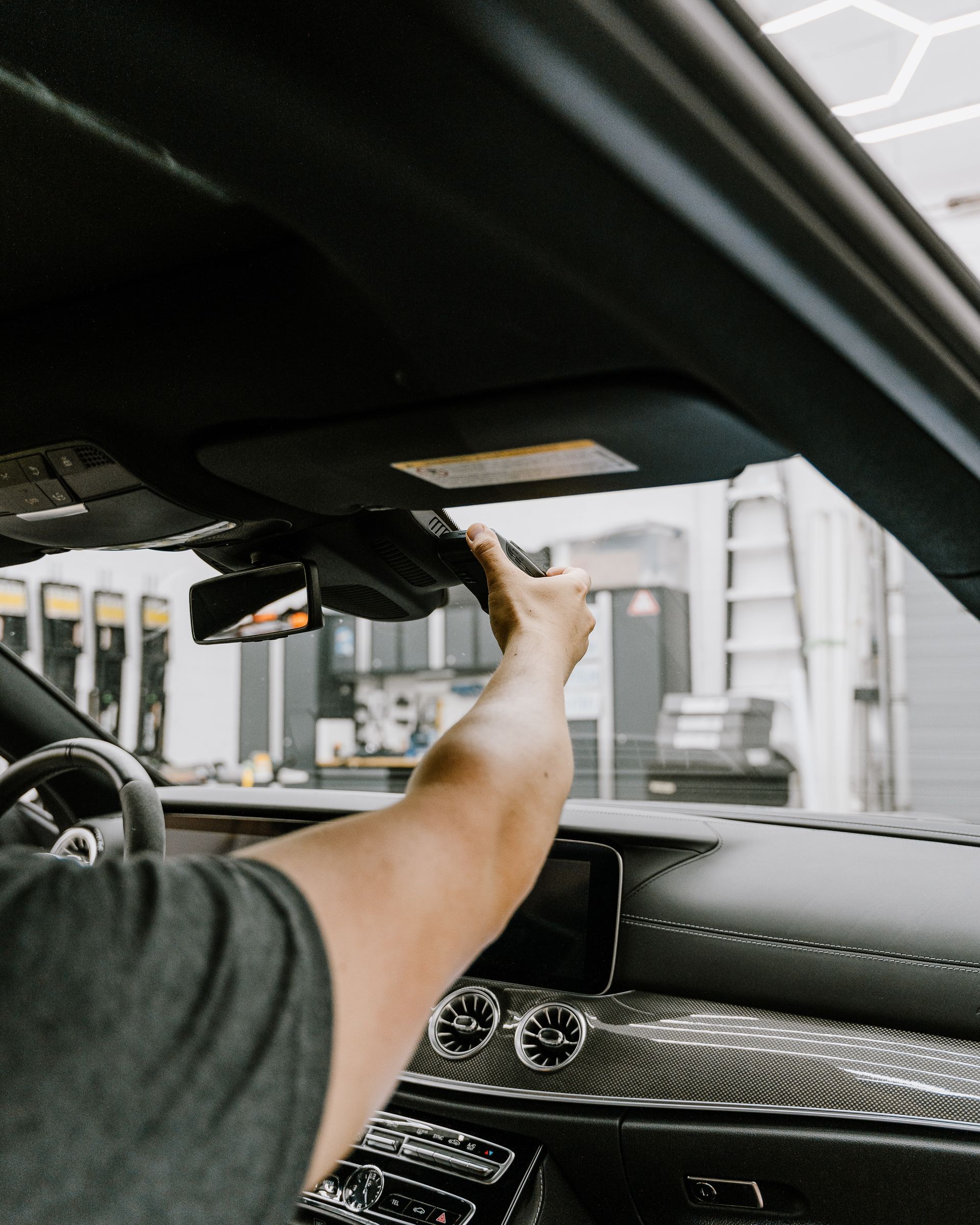 A man is driving a car with his hand on the steering wheel.