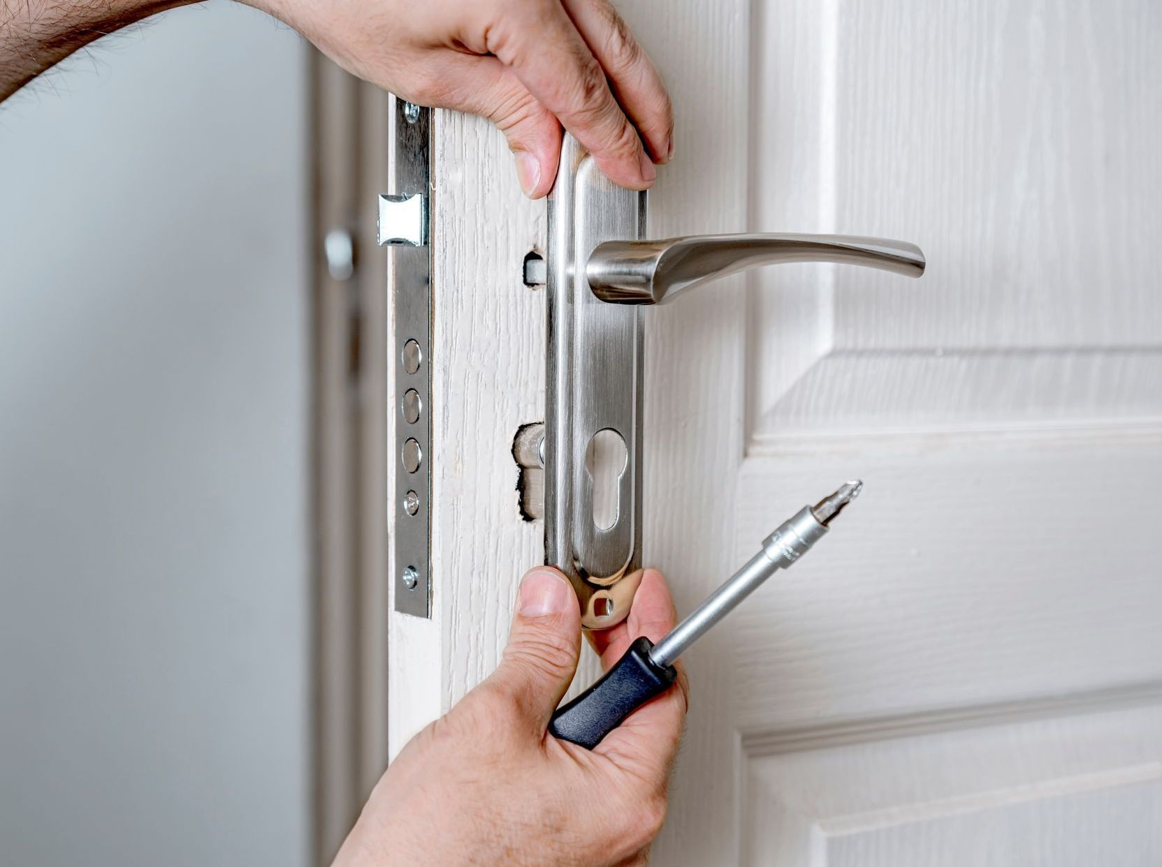 A person is fixing a door with a screwdriver.