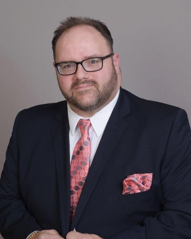 A man in a suit and tie is wearing glasses.