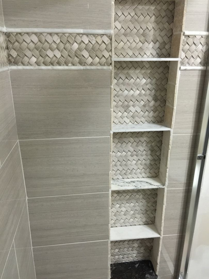Bathroom shower with tiled built-in shelves. Gray, beige, and patterned tile.