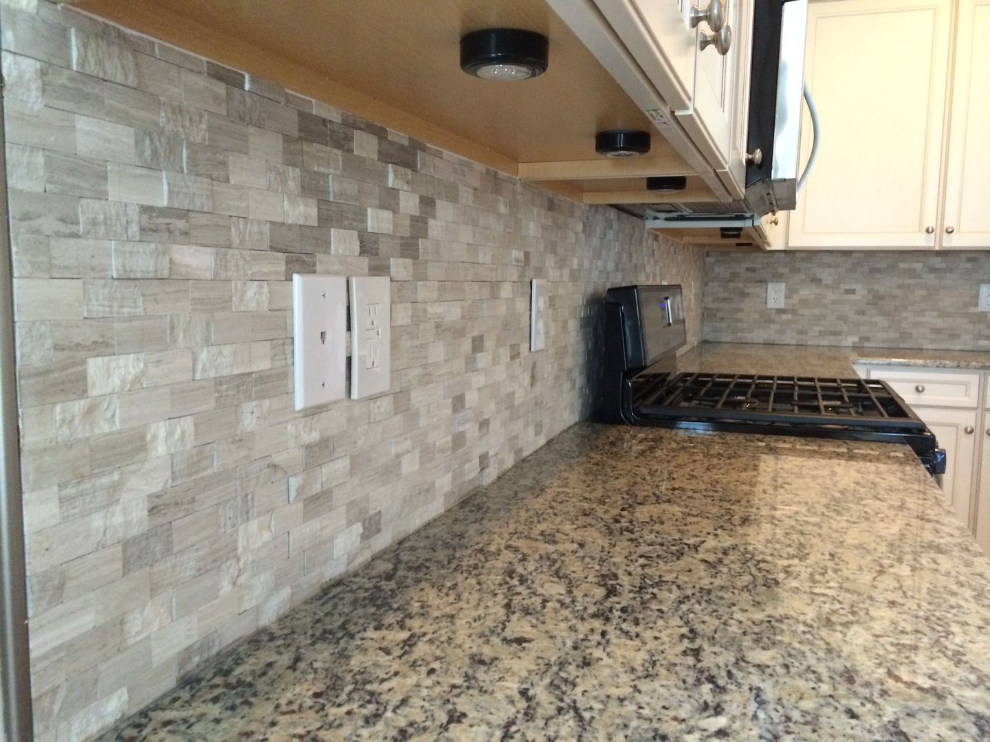 Kitchen with granite countertop, tiled backsplash, and white cabinets.