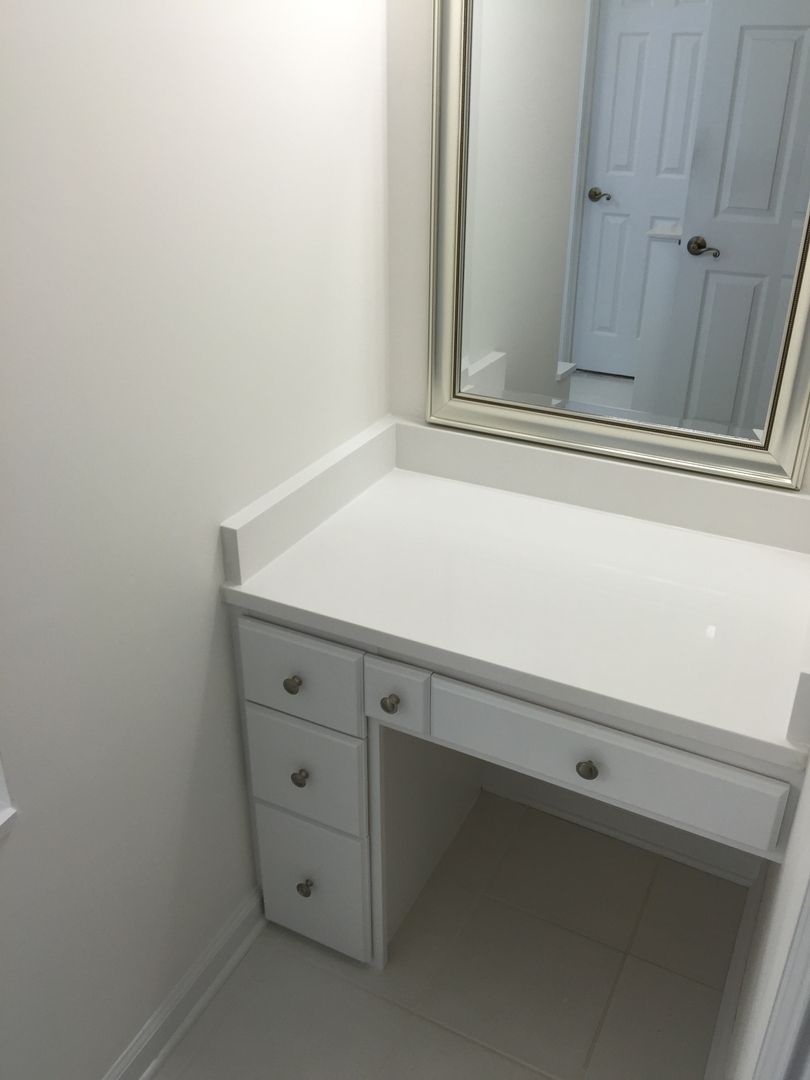 White vanity with drawers, a countertop, and a mirror in a bathroom.