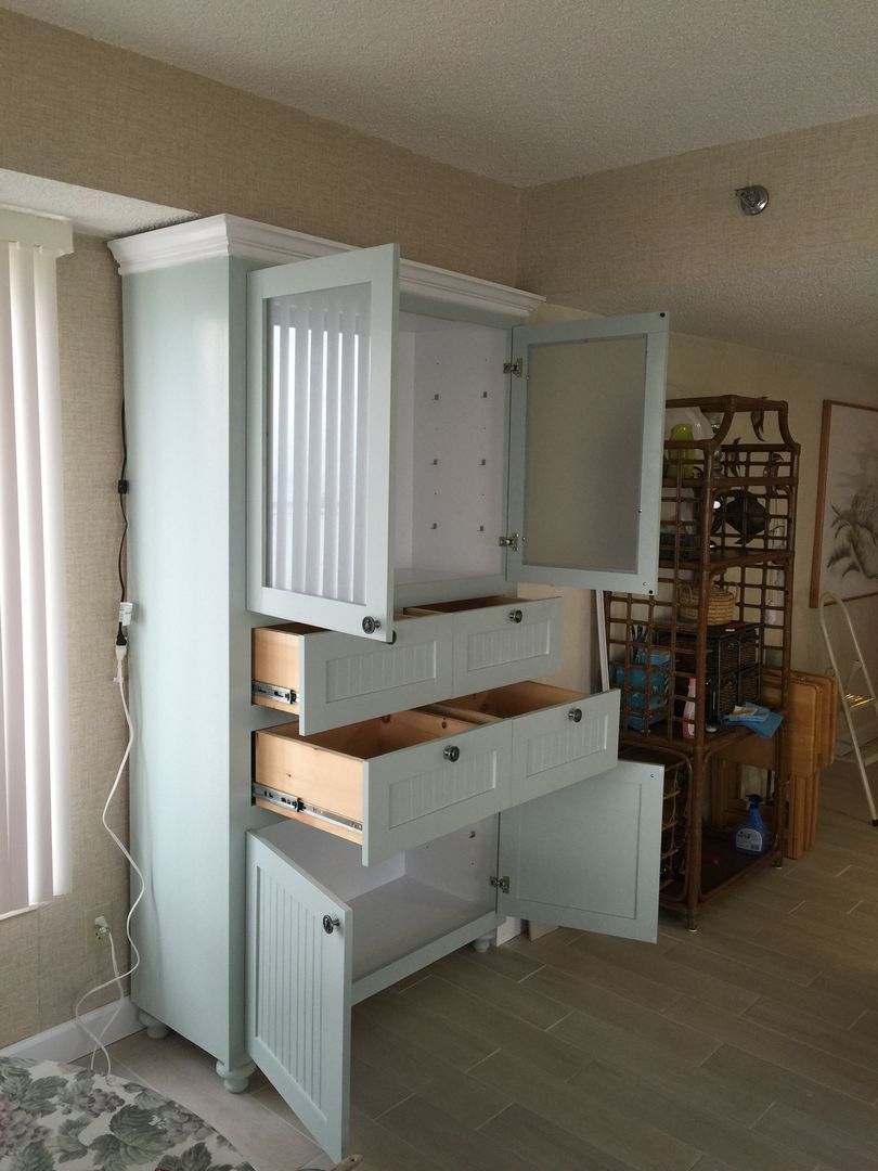 Blue cabinet with drawers and glass doors, open in a room.