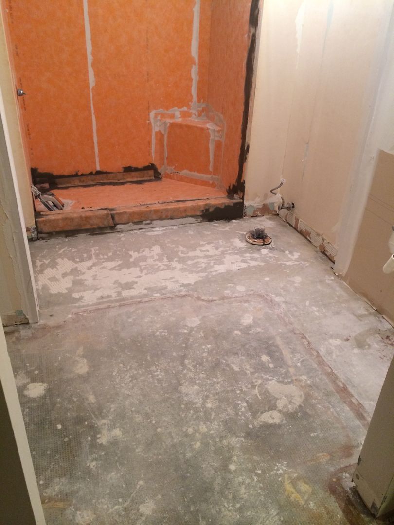 Bathroom remodel in progress; orange waterproof panels in shower, exposed concrete floor, and partial wall.
