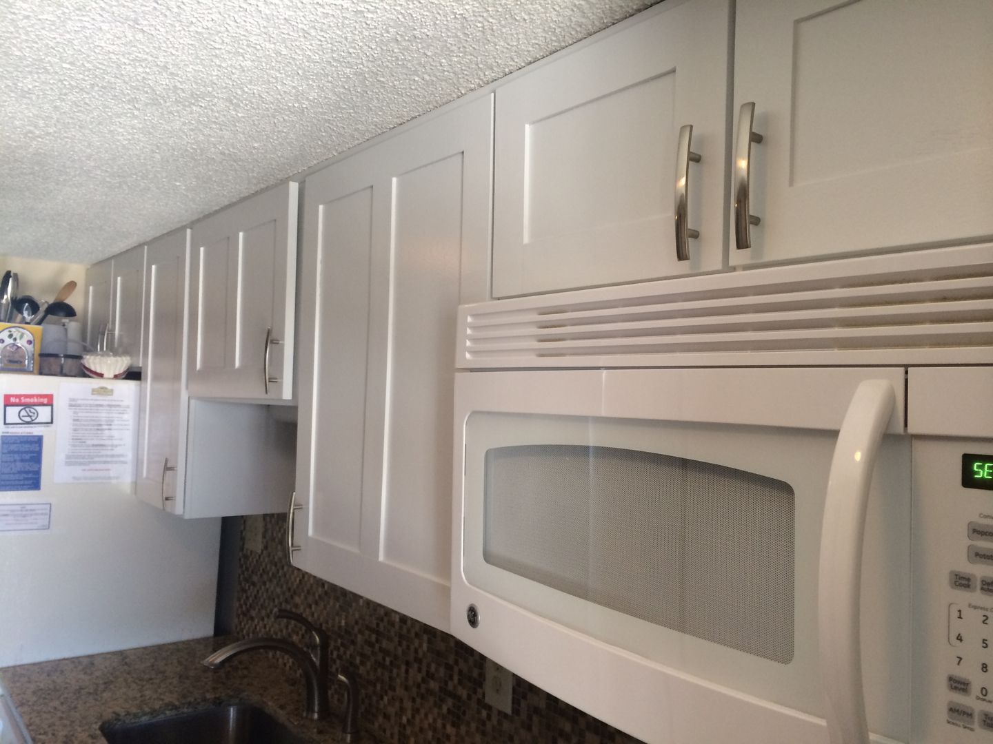White kitchen cabinets above a microwave and a granite countertop.