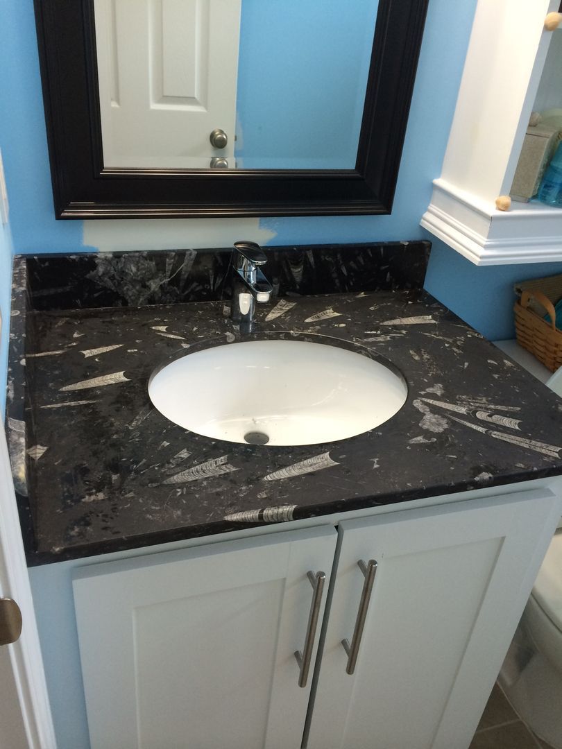 Bathroom vanity with a black and white patterned countertop, white sink, and black-framed mirror.