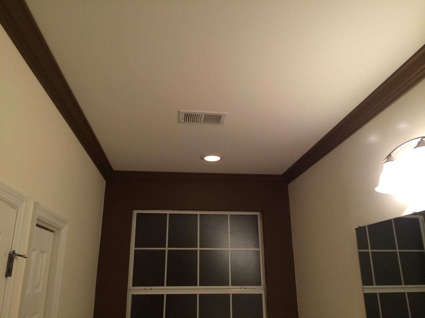 Ceiling with brown trim and a vent, with a window and a light fixture below.