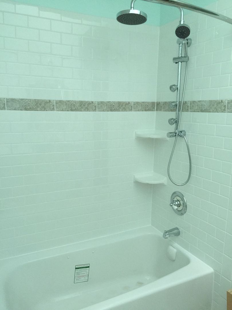 White tiled shower with a bathtub, showerhead, and two shelves.