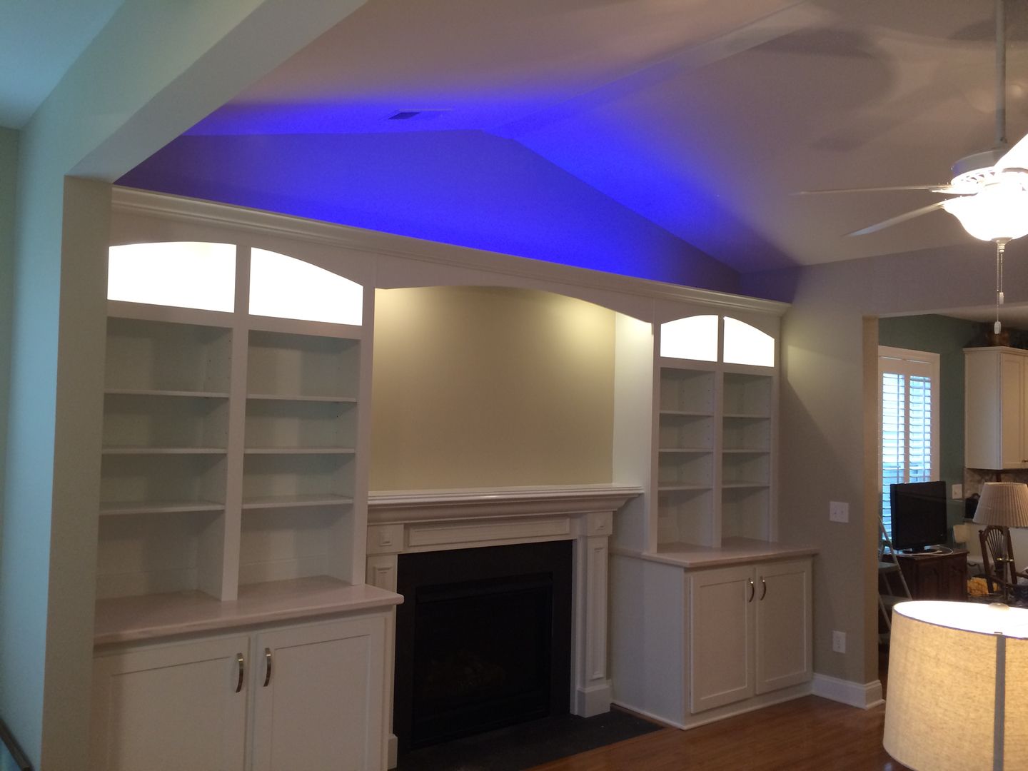 Built-in white bookshelves flanking a fireplace, with blue overhead lighting.