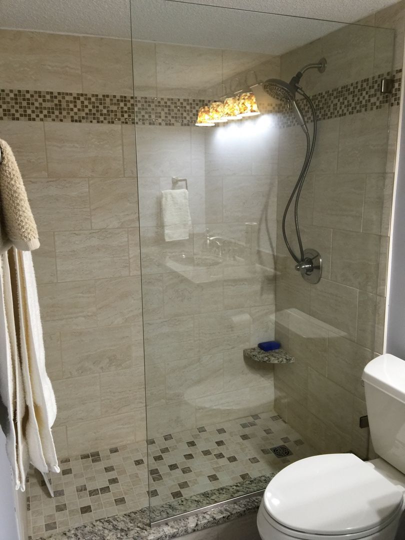 Bathroom with tile walls, glass shower door, and a toilet.