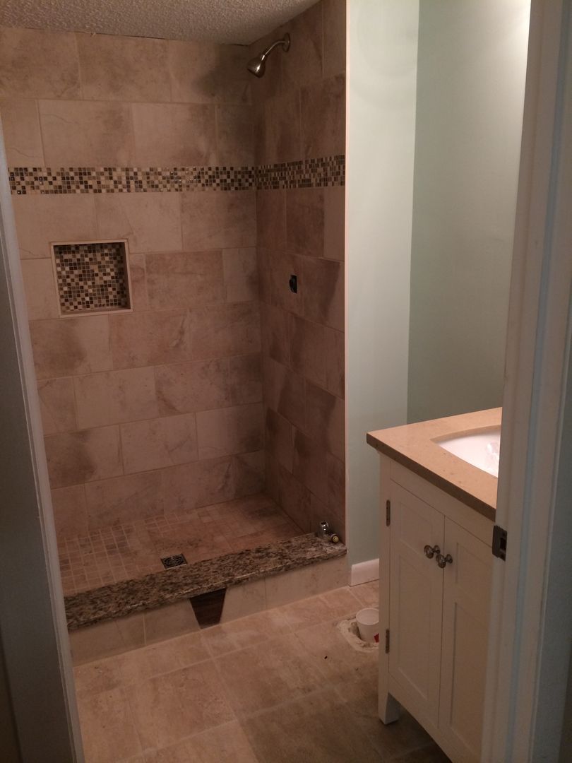 Bathroom with tiled shower, small pebble shower base, and vanity with sink.