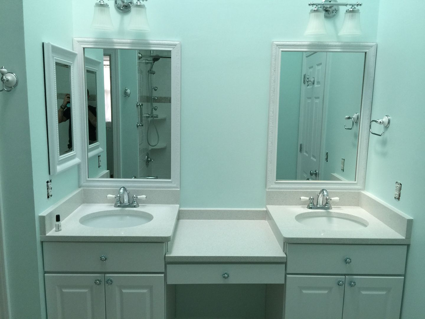 Two white vanity sinks, mirrors, and lights on a light blue wall.