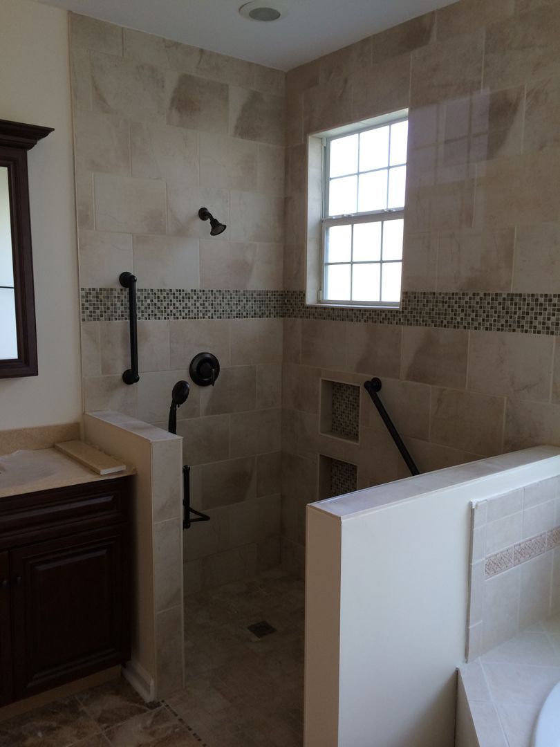 Tiled shower with grab bars, shower head, faucet, and a small window.