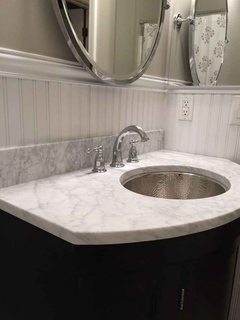 Bathroom vanity with a marble countertop, metallic sink, and chrome faucet.