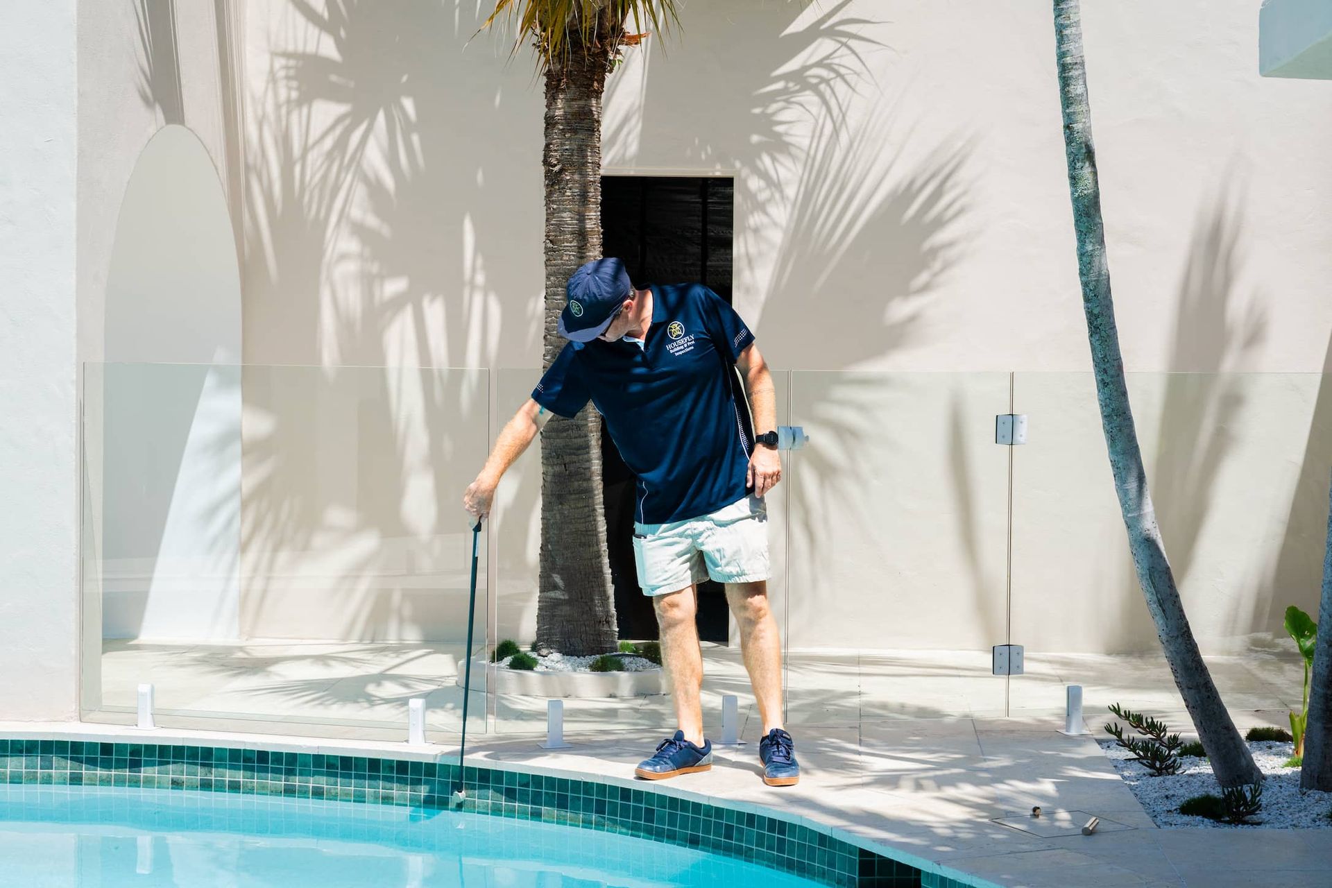 A man is cleaning the edge of a swimming pool.