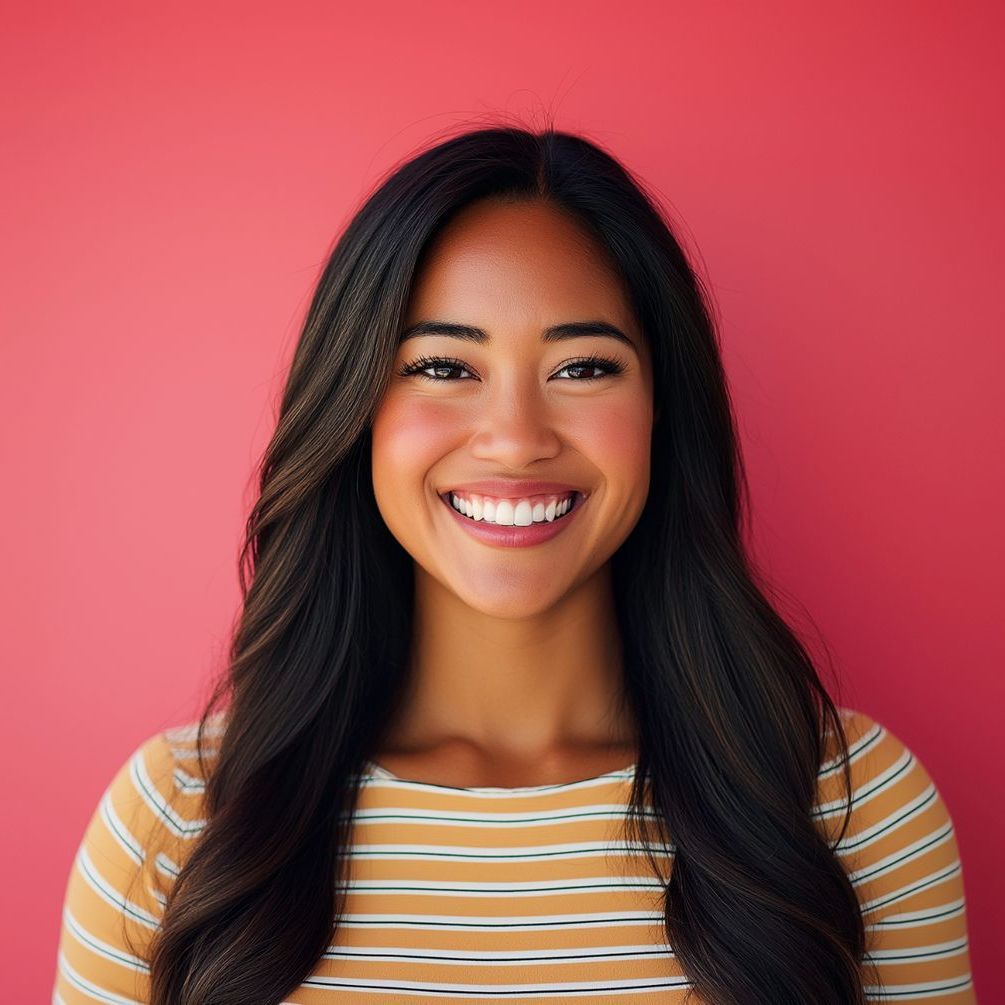A woman in a striped shirt is smiling in front of a pink wall.