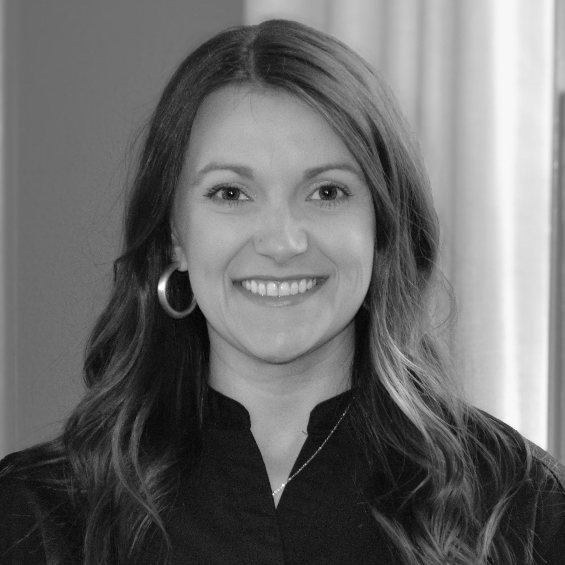 Ashleigh is an orthodontic assistant and is smiling in front of a brick wall.