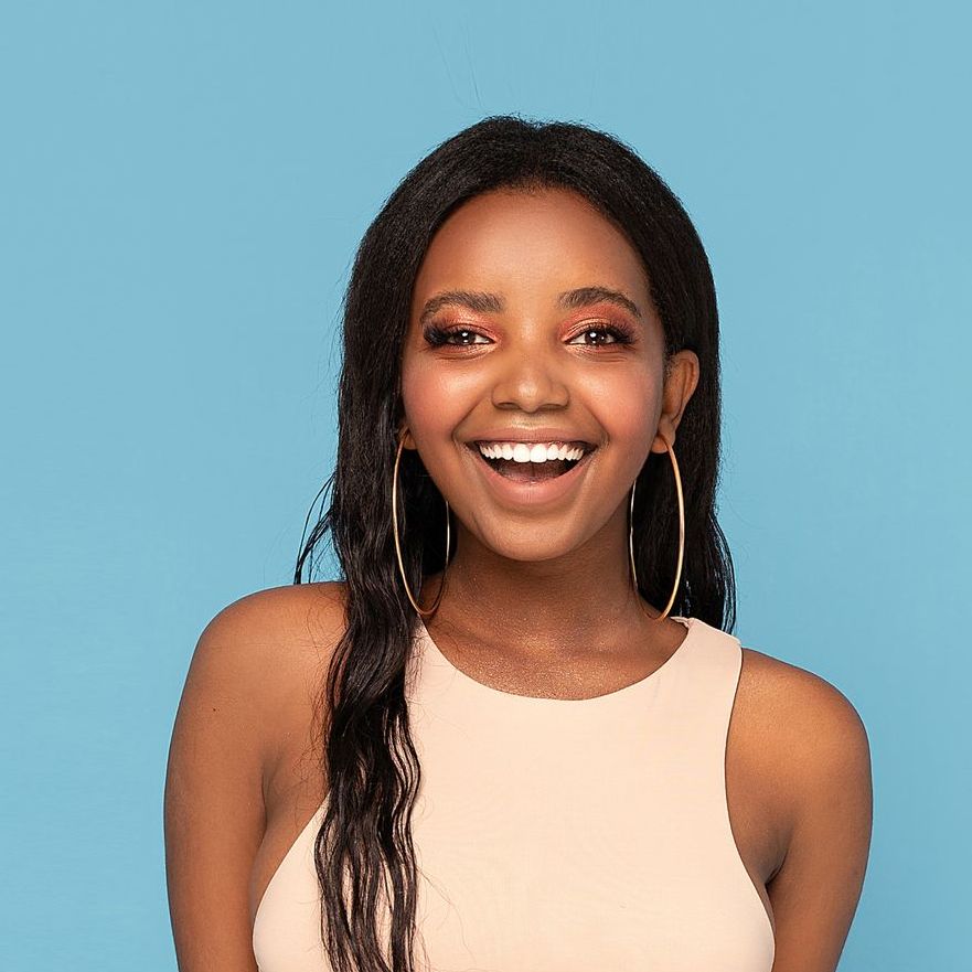 A woman wearing hoop earrings and a tank top is smiling.