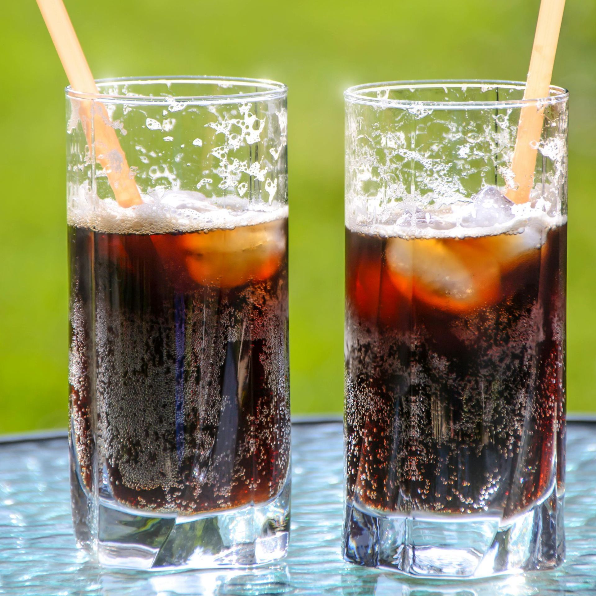 Two glasses of soda with straws on a table