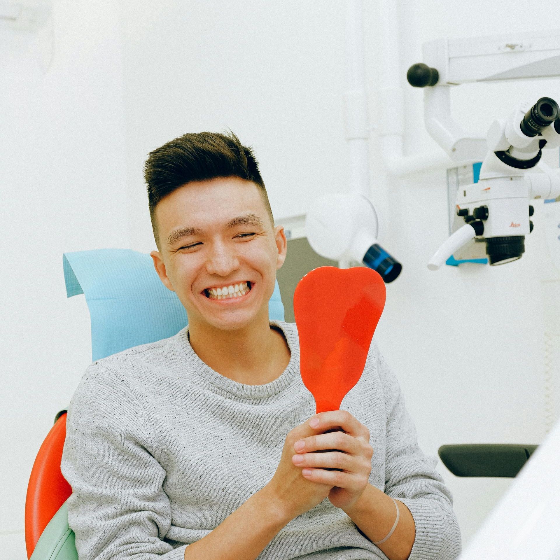 A man sitting in a dental chair holding a red heart shaped object