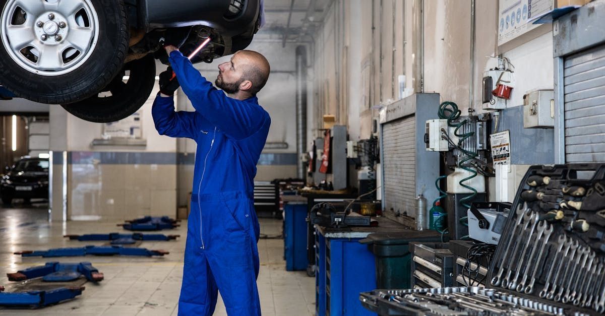 A man is working on the underside of a car in a garage. | On The Go Garage