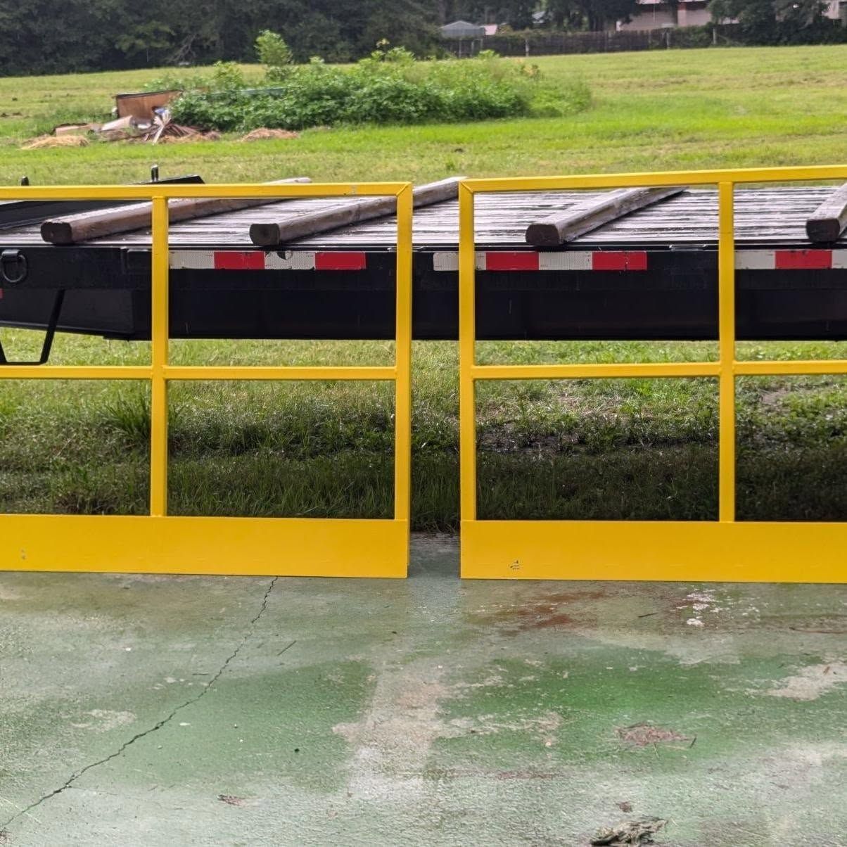 Yellow safety gates in front of a trailer on grass.