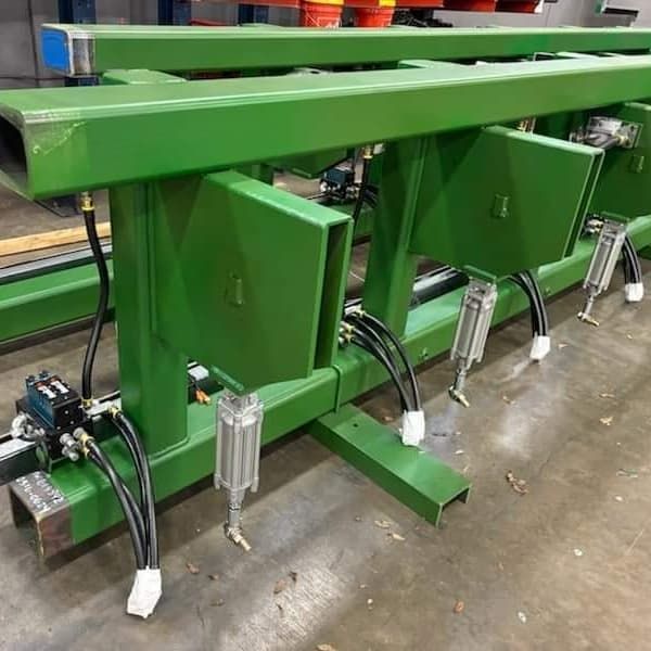 Green industrial machine with pneumatic cylinders and hoses.