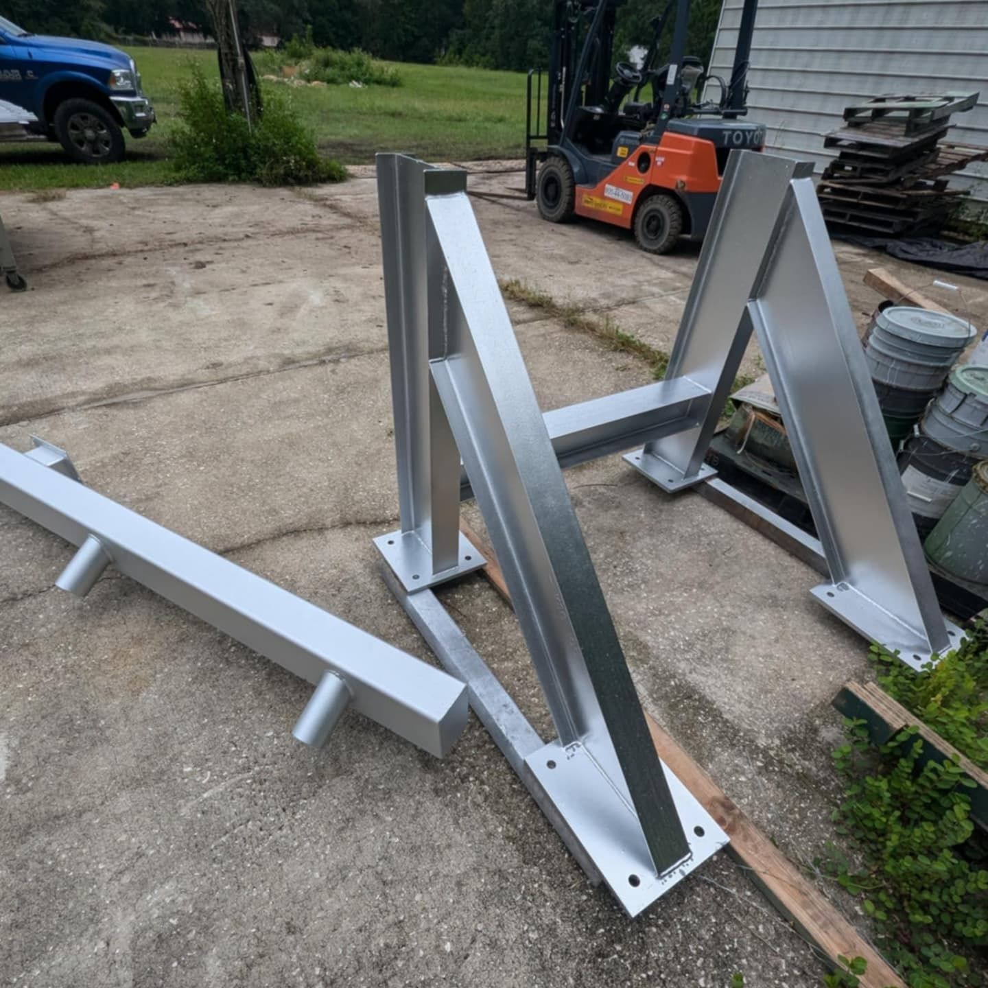 Aluminum metal framework, likely for construction, in an outdoor setting with a forklift visible.