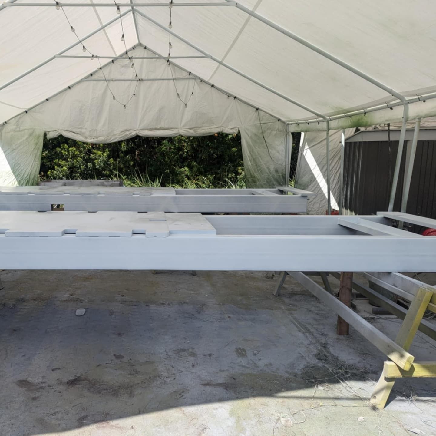 Gray-painted wooden door frame on a work surface under a white tarp.