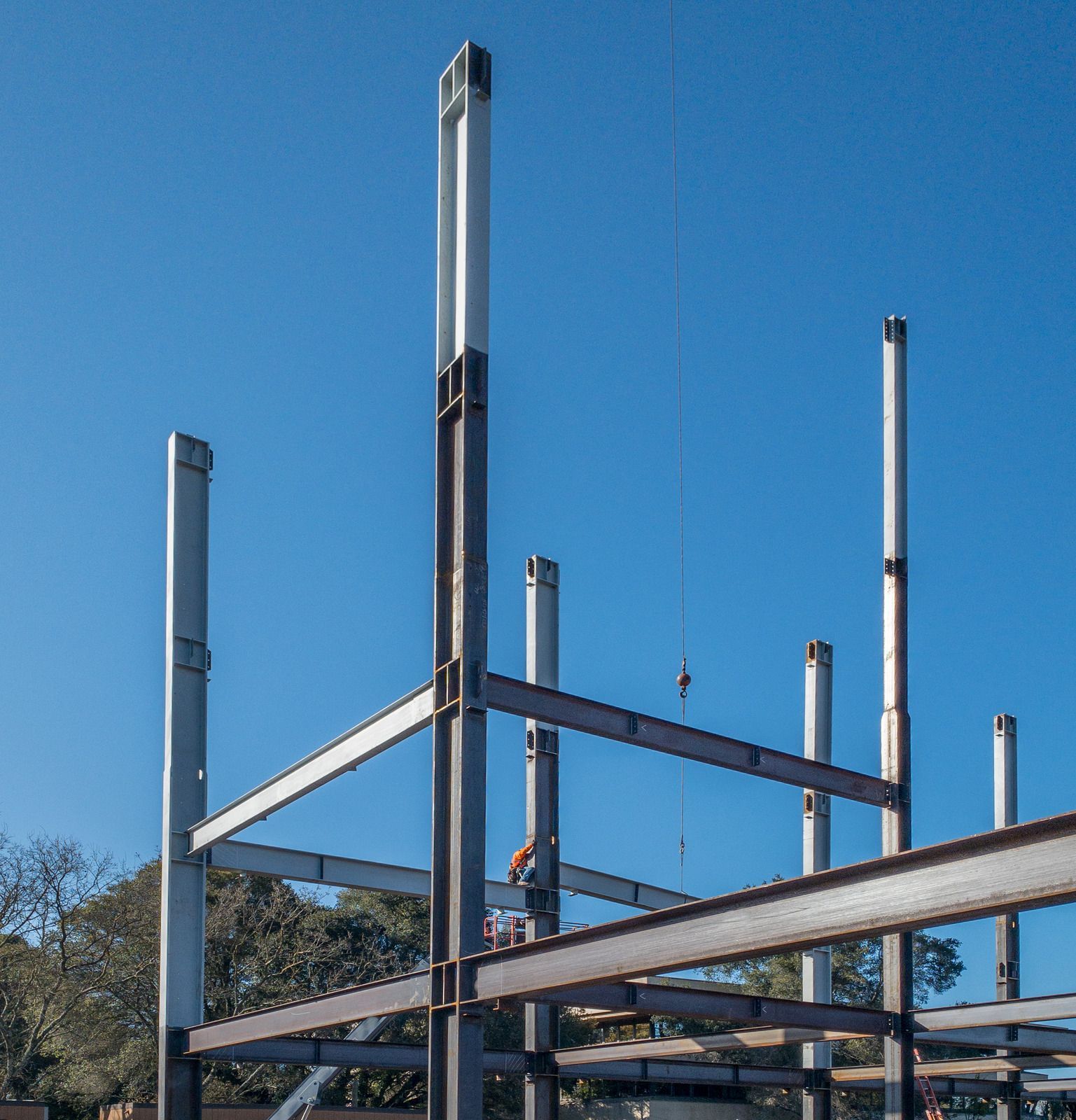 Steel framework of a building under construction against a clear blue sky.