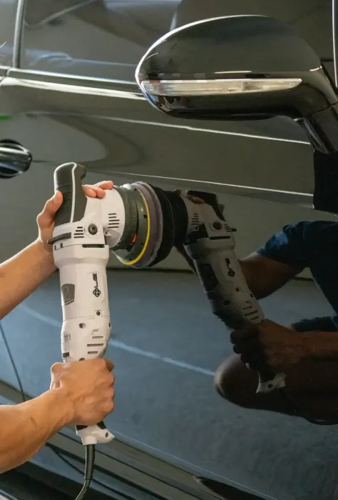 A person is polishing a car with a machine.