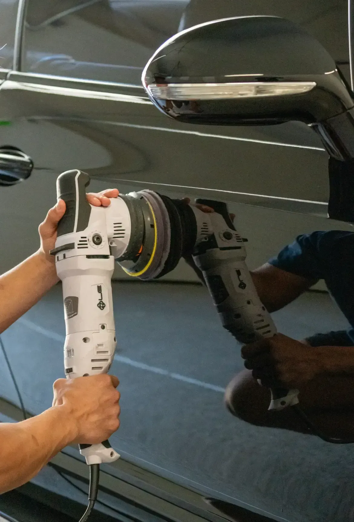 A person is polishing a car with a machine.