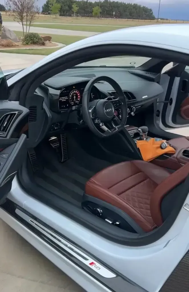 The interior of a white car with brown seats and a steering wheel.