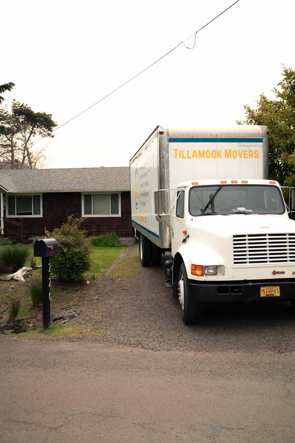 A white moving truck is parked in front of a house