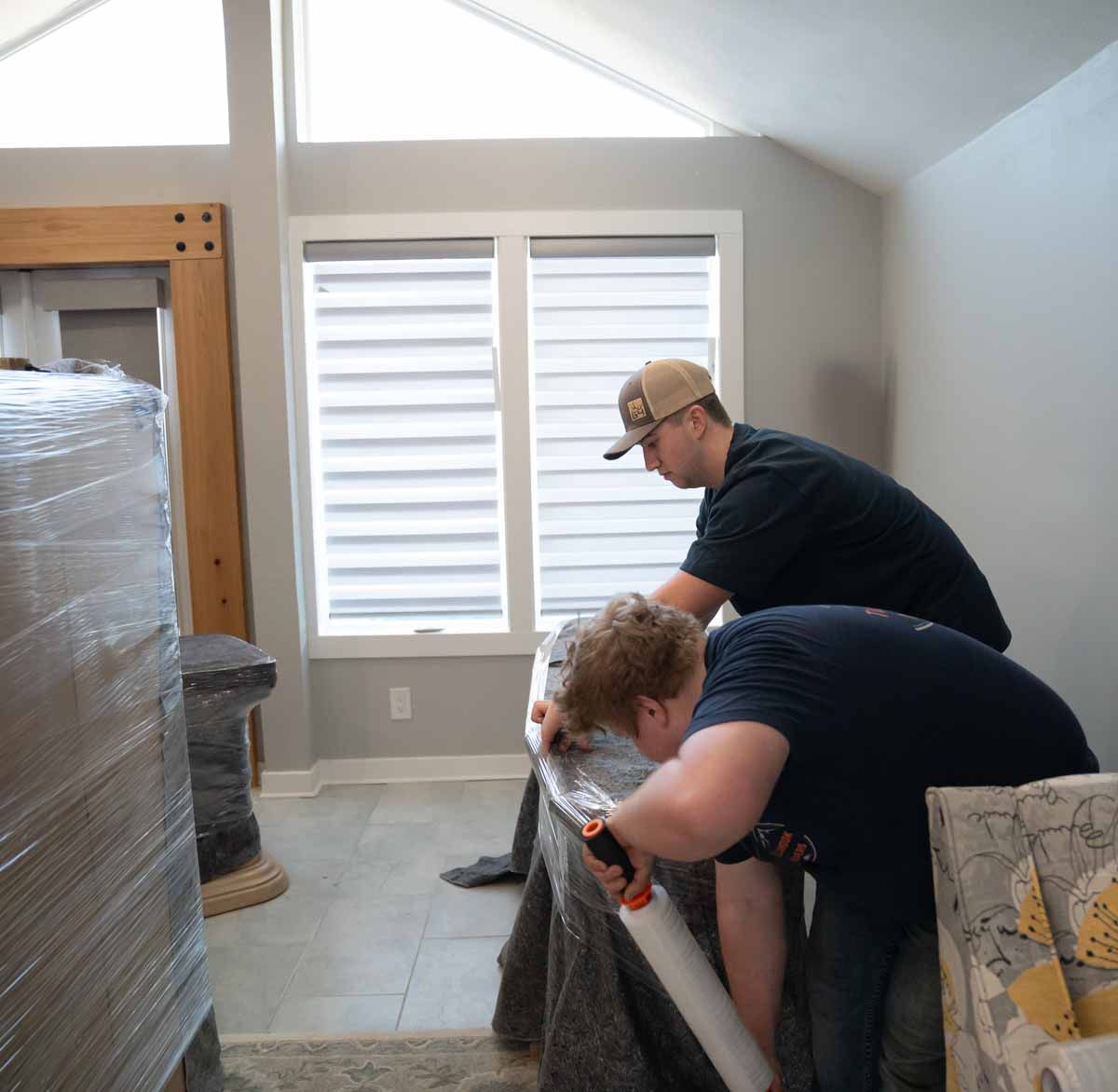Two men are working on a piece of furniture in a living room.