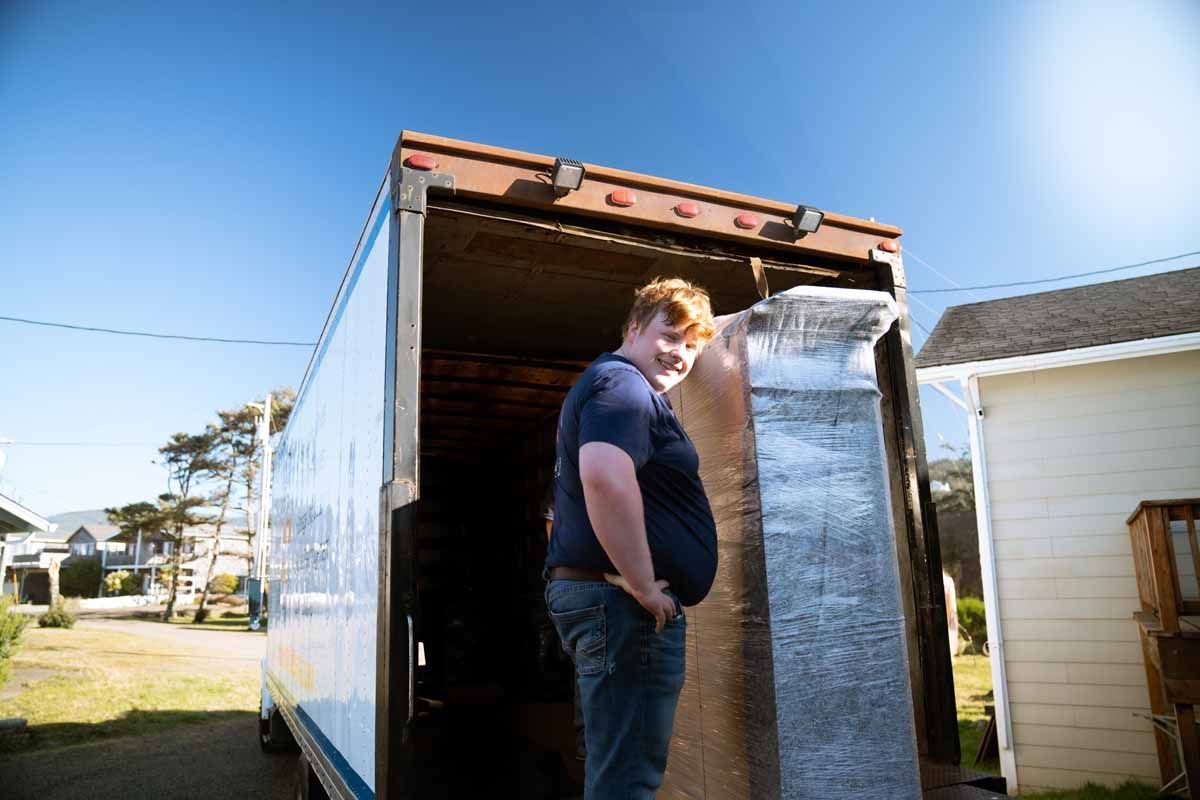 A man is standing in the back of a moving truck.