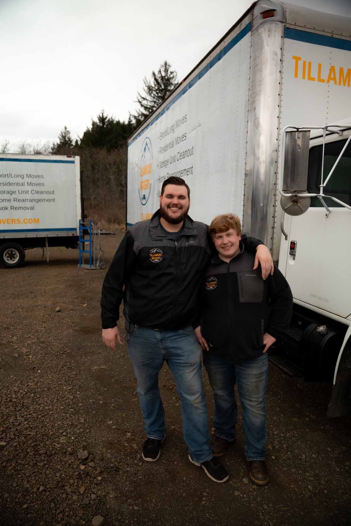 Two men are posing for a picture in front of a truck.