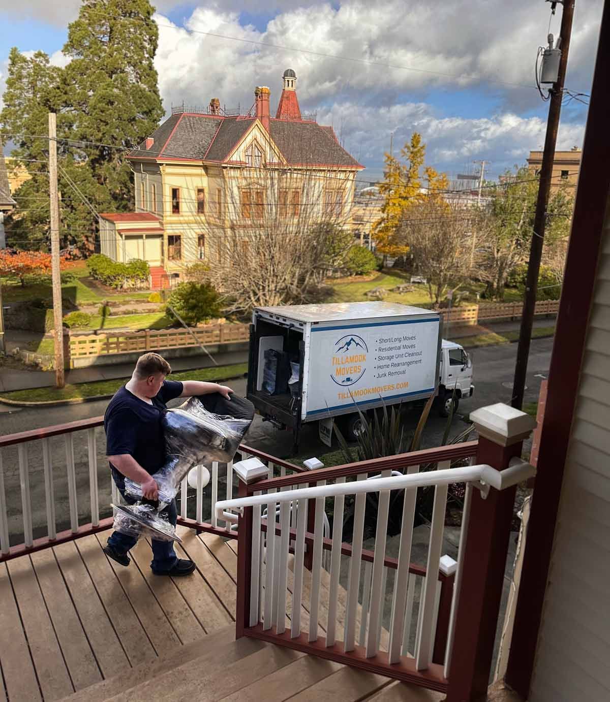 A man is carrying a box up a set of stairs next to a truck.